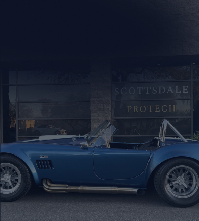 Blue classic car parked in front of a building that says 
