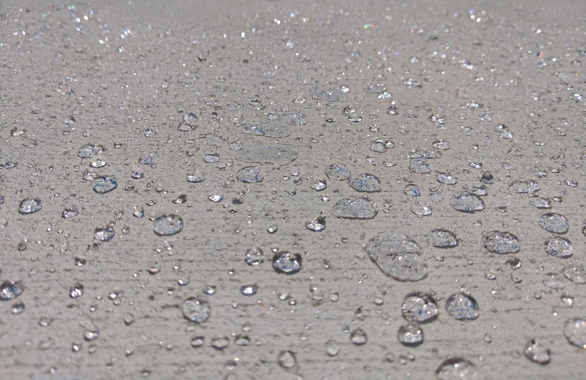 A sealed concrete surface with water drops on it.