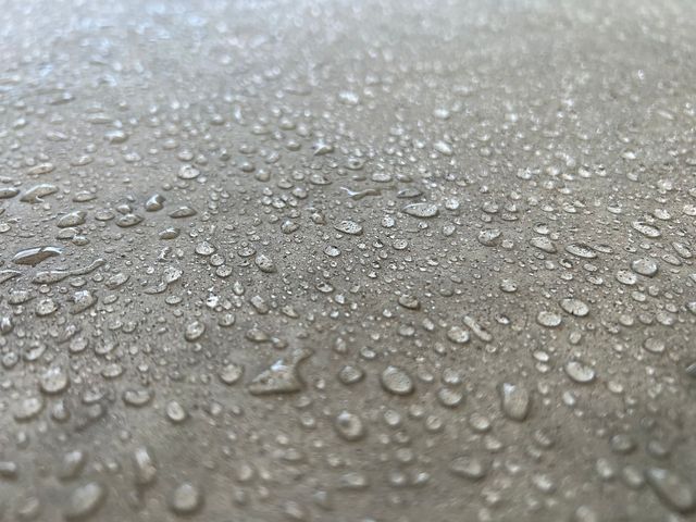 A close up of water drops on a sealed concrete surface.