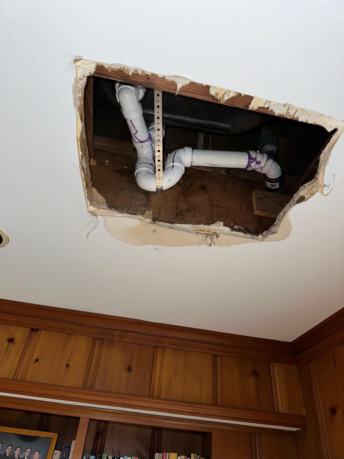 A hole in the wall is made to reach the pipes to do the plumbing repair necessary. 