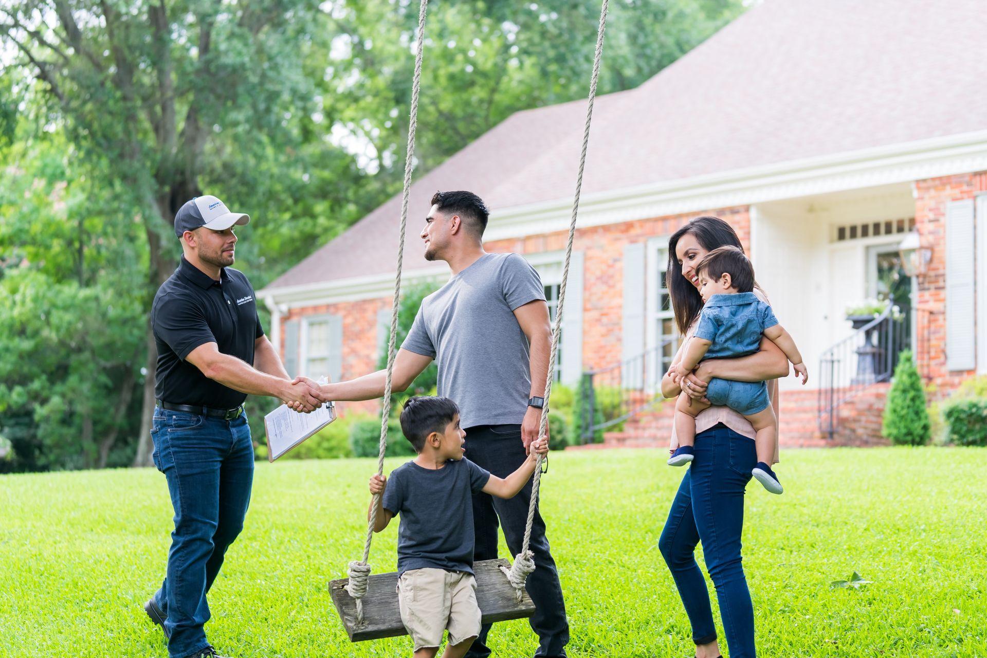 Couple in a living room, seated and relaxing. Gray sofa, large window, potted plants, floor lamp.