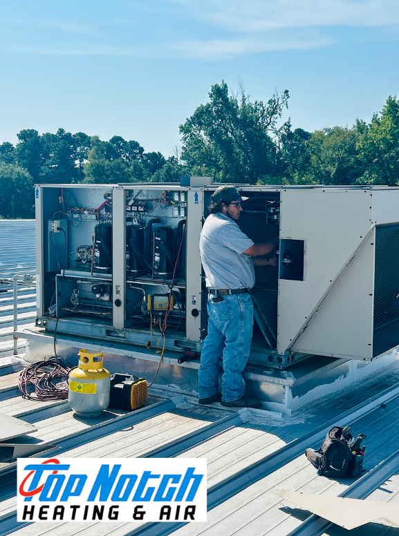 A technician works on a commercial HVAC unit on a rooftop, with a logo for Top Notch Heating & Air in the foreground.