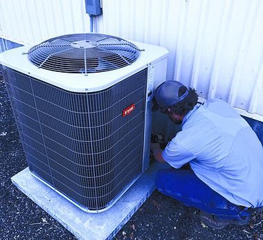 Person working on a Bryant air conditioning unit outside a building.