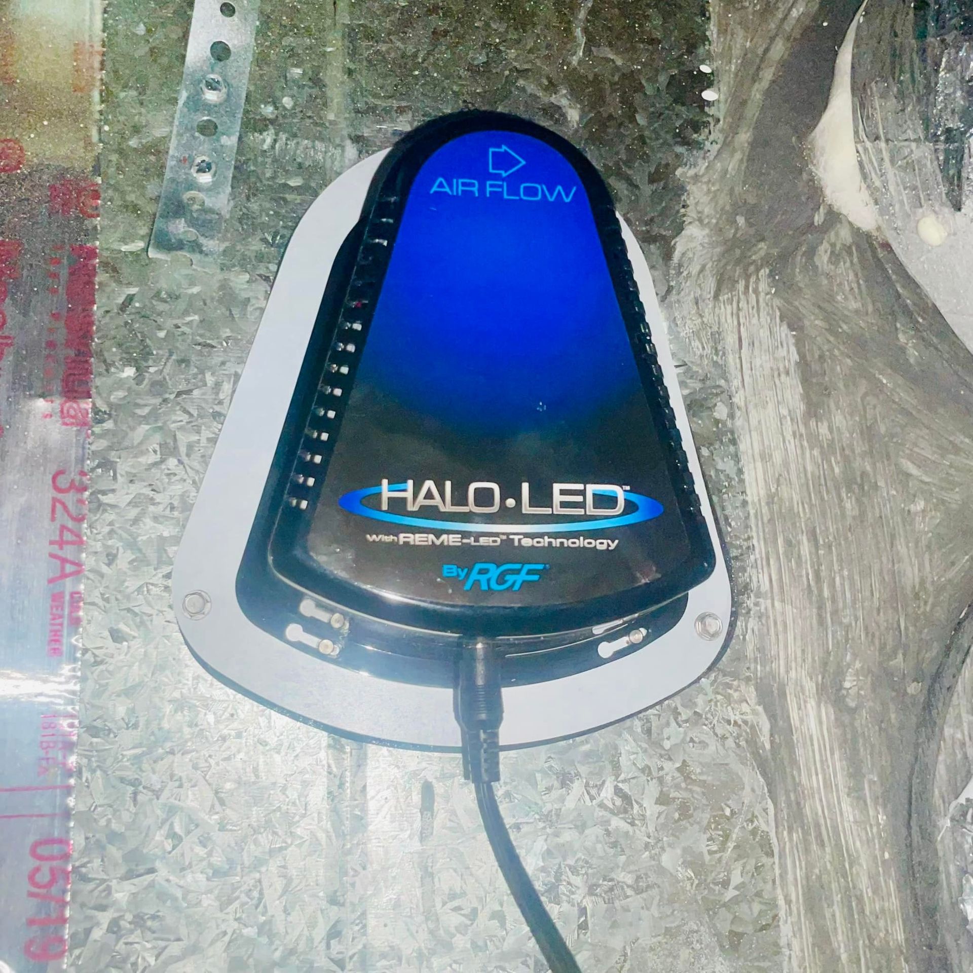 A black HALO-LED air purification device mounted on a metal duct, glowing with a blue light.