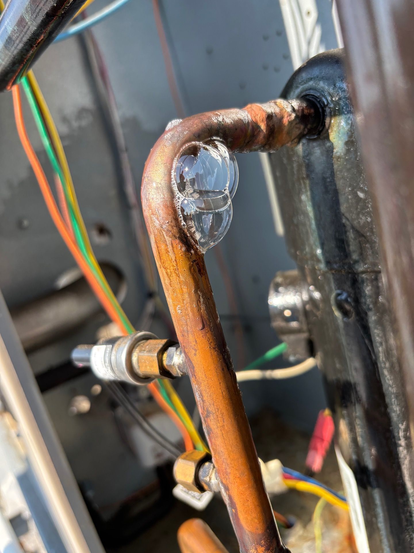 Close-up of frozen copper refrigerant tubing on an outdoor air conditioning unit compressor.
