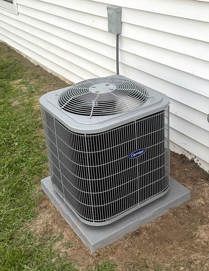 A gray residential outdoor air conditioning unit on a concrete pad next to white vinyl siding.