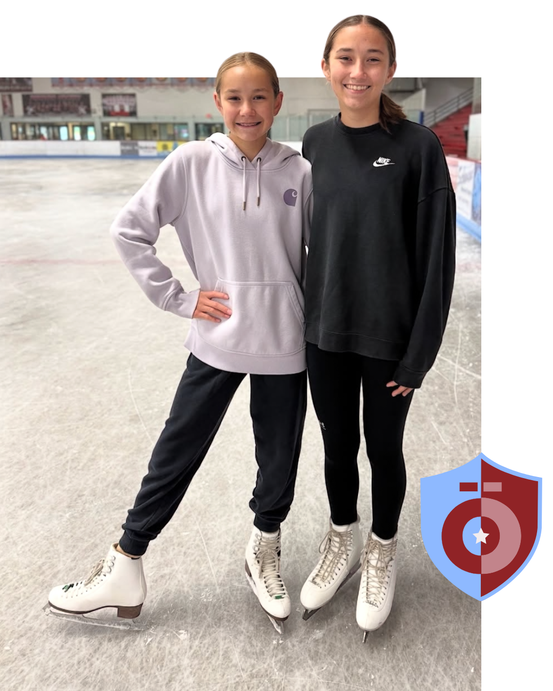 Two people in hoodies and ice skates posing together on an indoor ice rink.