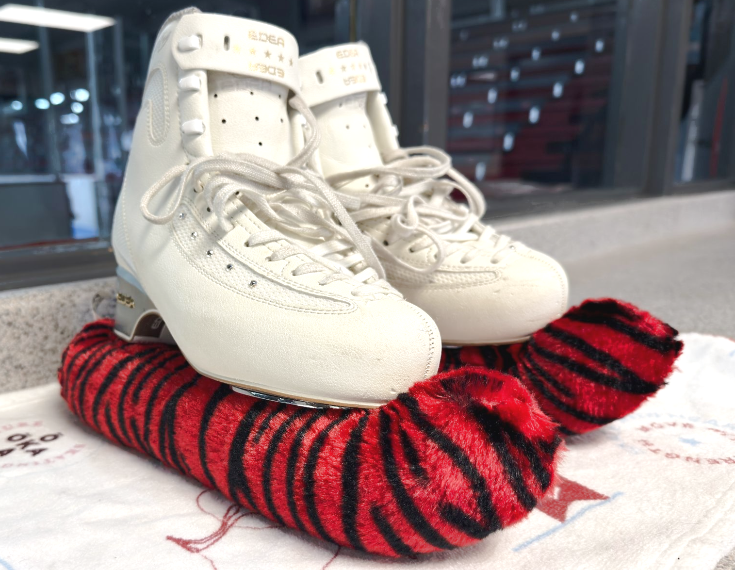 White ice skate with pink fur blade covers.