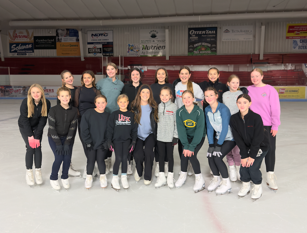 Four people wearing ice skates on ice, close-up of legs.