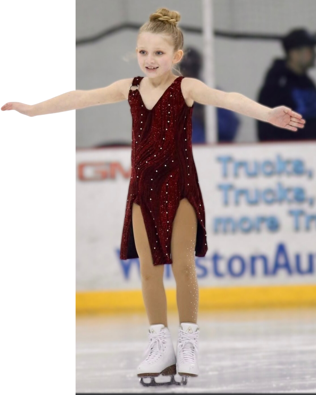 Young figure skater in a maroon dress, arms outstretched, on the ice.