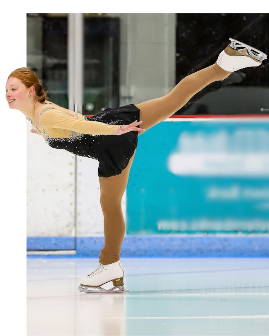 Figure skater in black and purple dress, pointing, smiling on ice rink.