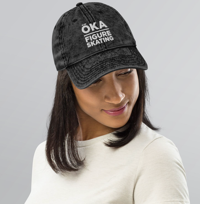 Woman wearing a black denim cap with white text that reads 