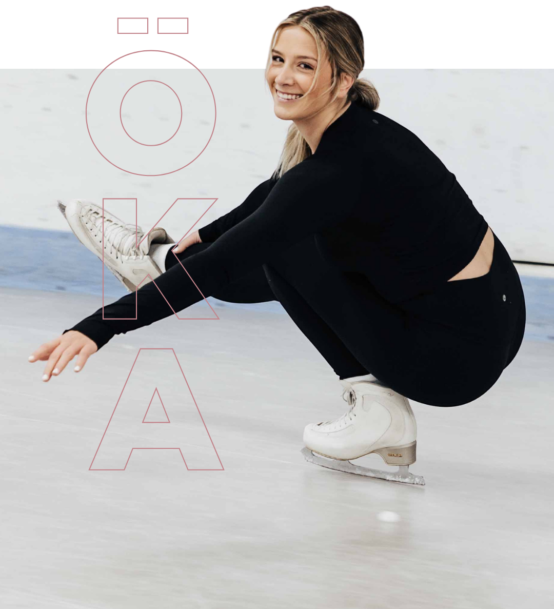 Woman on ice skates, in black athletic wear, smiling, in a squat position on an ice rink.