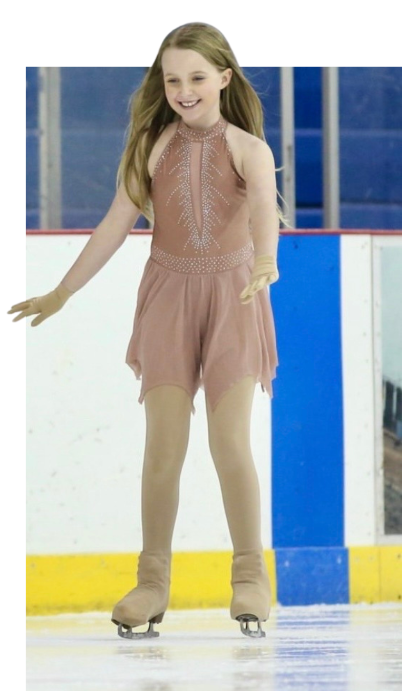 Girl in a pink skating dress on an ice rink, smiling with arms outstretched.