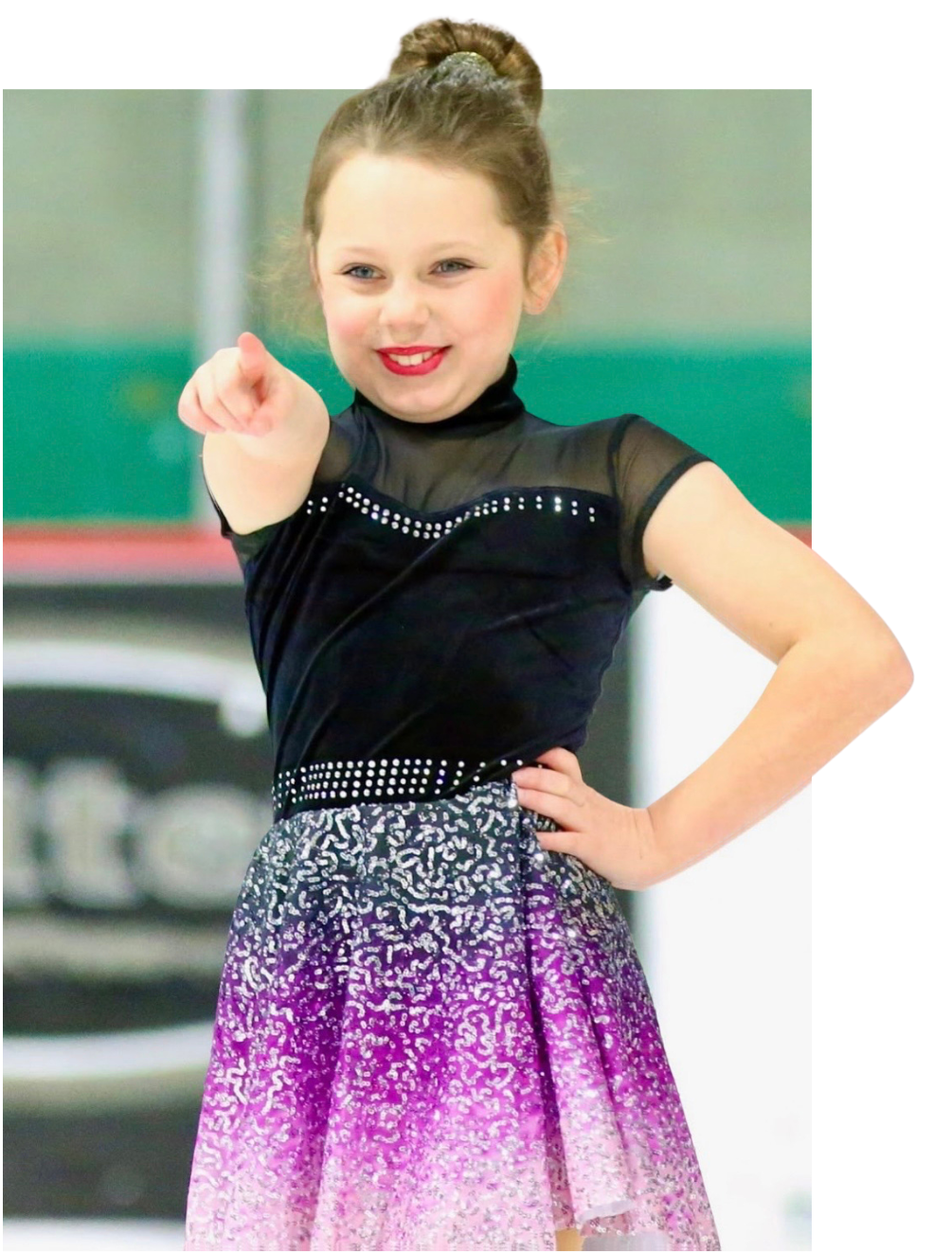 Young figure skater in black and purple dress, pointing. Ice rink background.