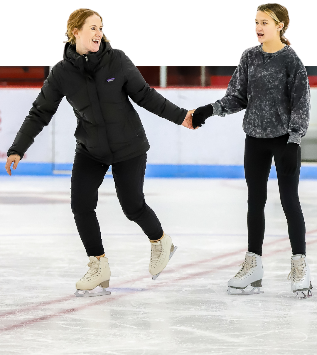 Woman in black jacket and girl in sweater ice skate together on rink, holding hands.