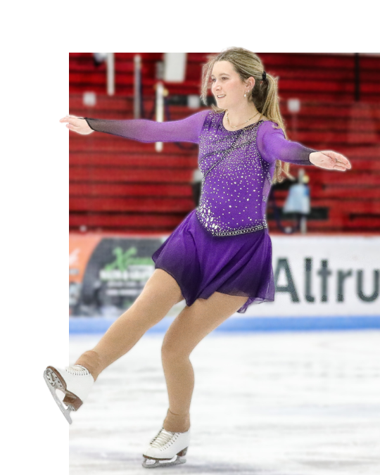 Young figure skater in light blue dress smiles on the ice rink.
