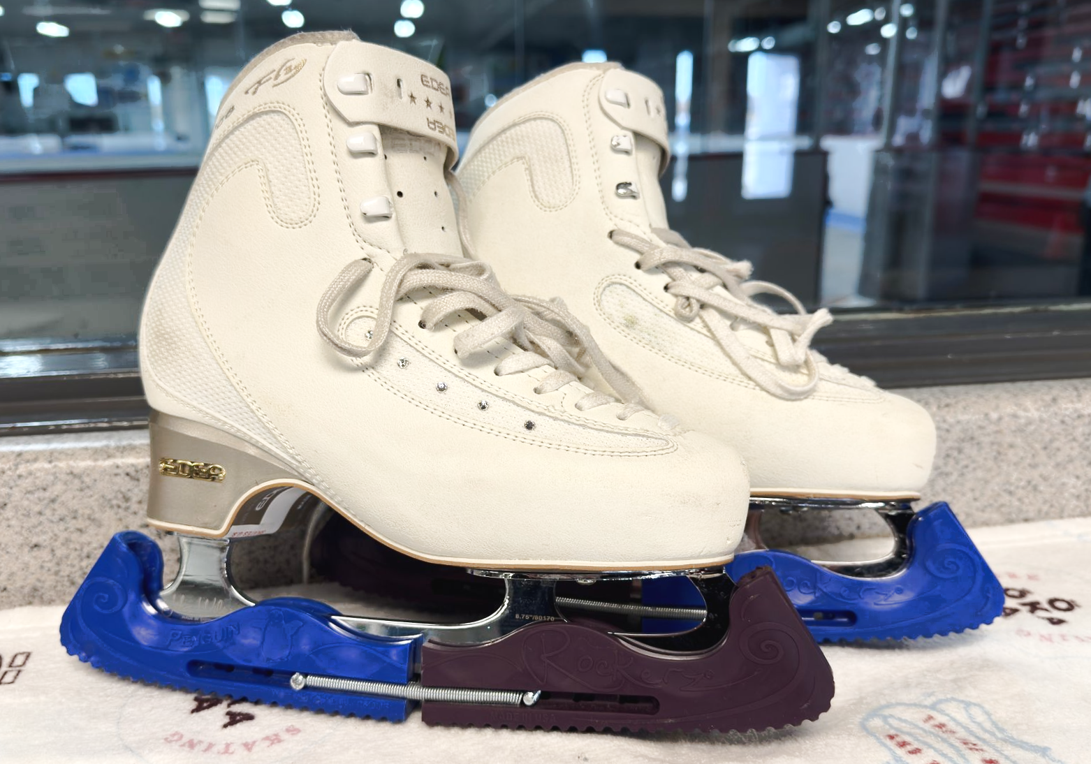 Ice skates with colorful blade guards, indoors.
