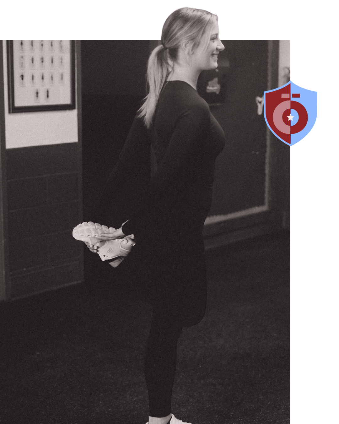 Woman stretching her leg, holding foot behind her. Indoor setting, black and white.