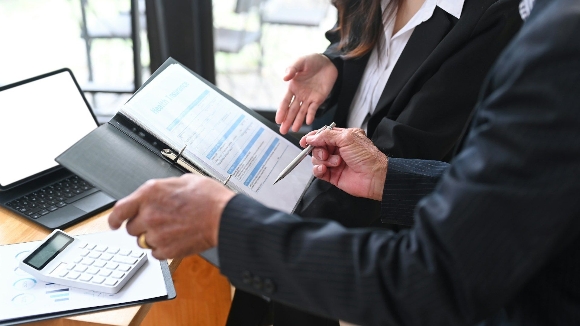 Two people reviewing paperwork in an office setting; one person pointing with a pen.