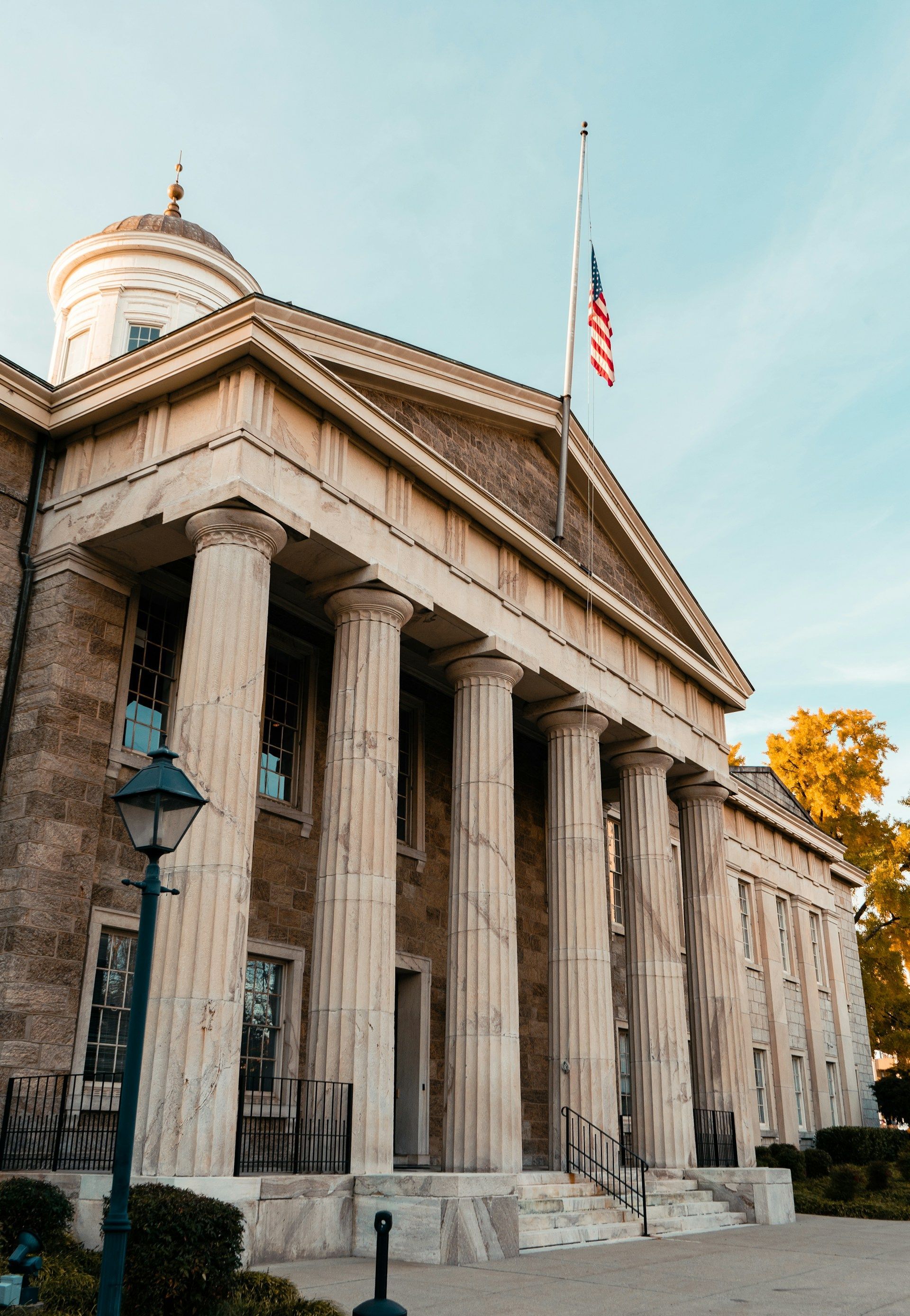 A woman with a wide smile hugs a young boy tightly, both indoors near a window.
