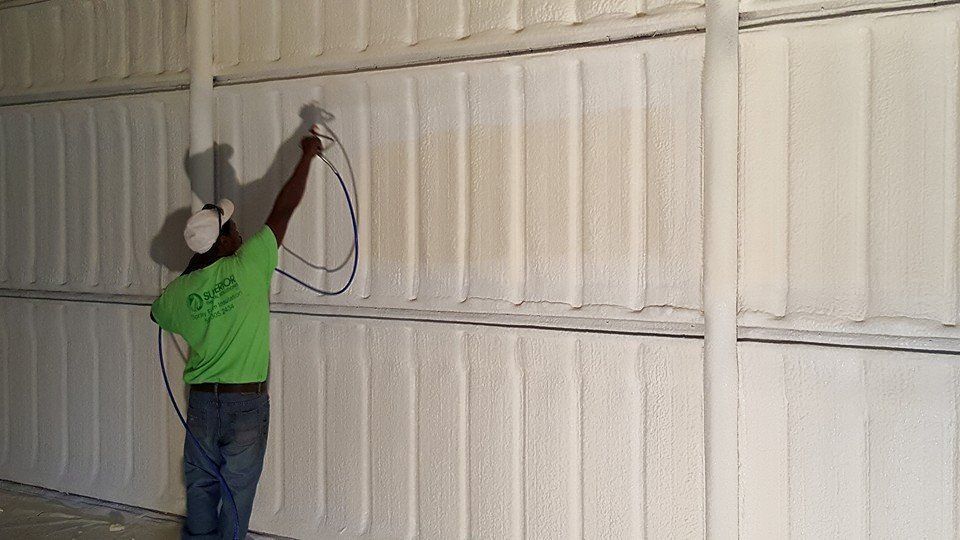 Woman in straw hat smiles, holding wine glass near a lake.