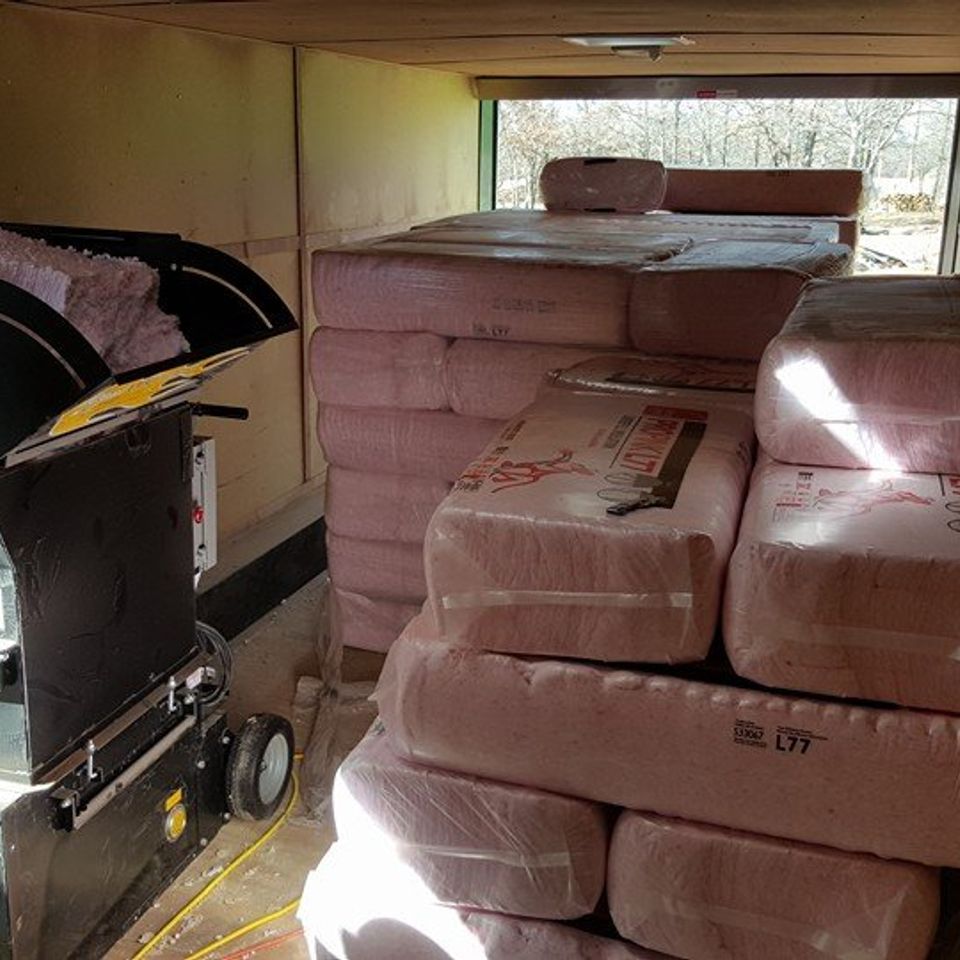 Woman in straw hat smiles, holding wine glass near a lake.