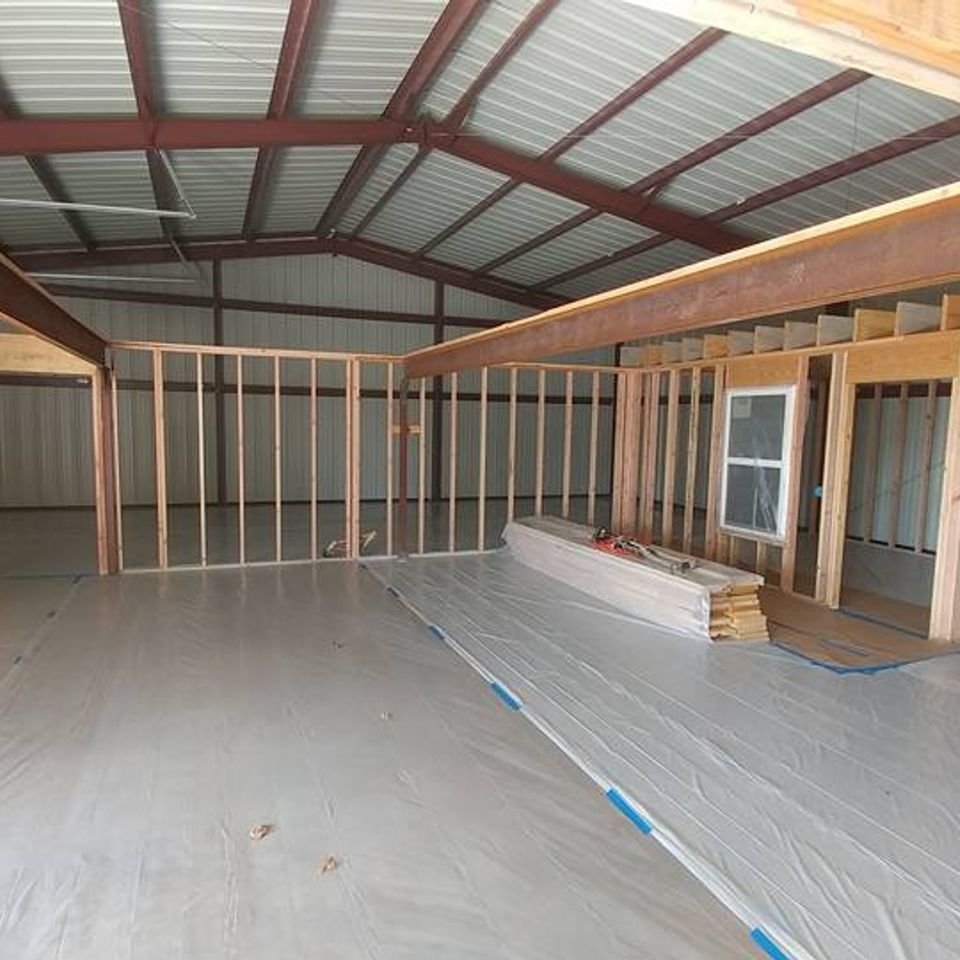 Woman in straw hat smiles, holding wine glass near a lake.