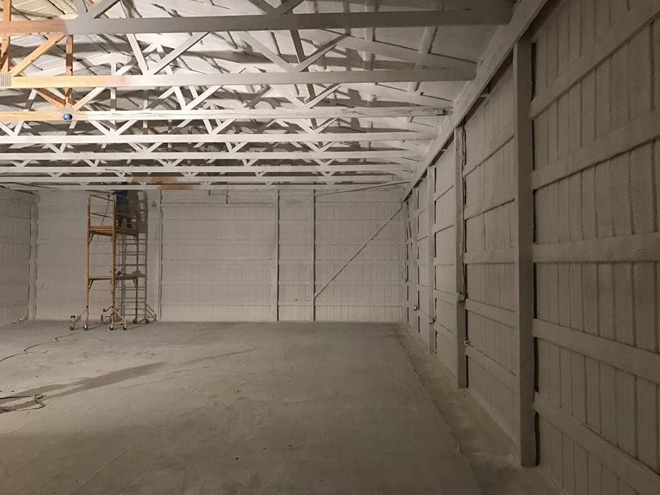 Woman in straw hat smiles, holding wine glass near a lake.