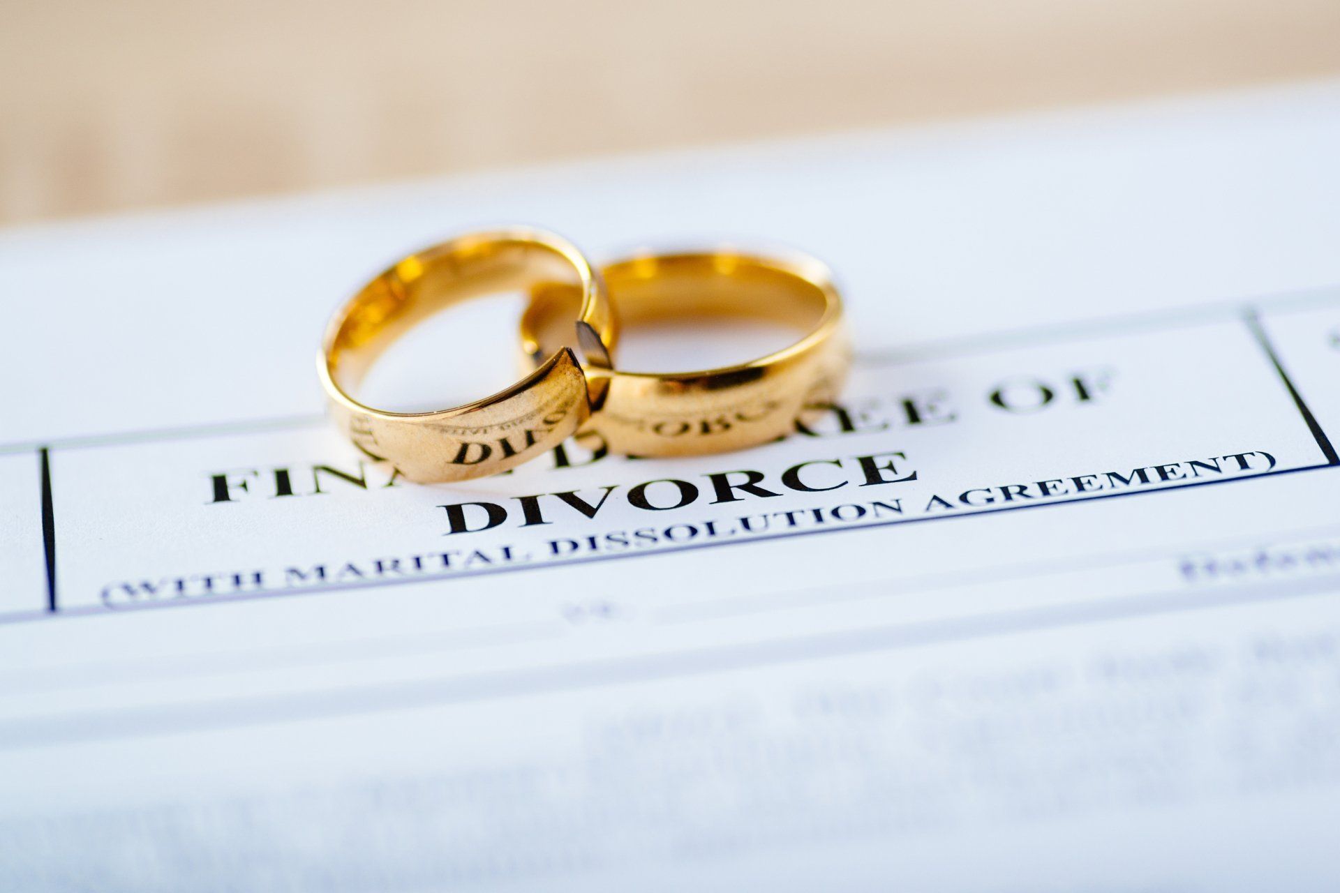 Two broken golden wedding rings divorce decree document.