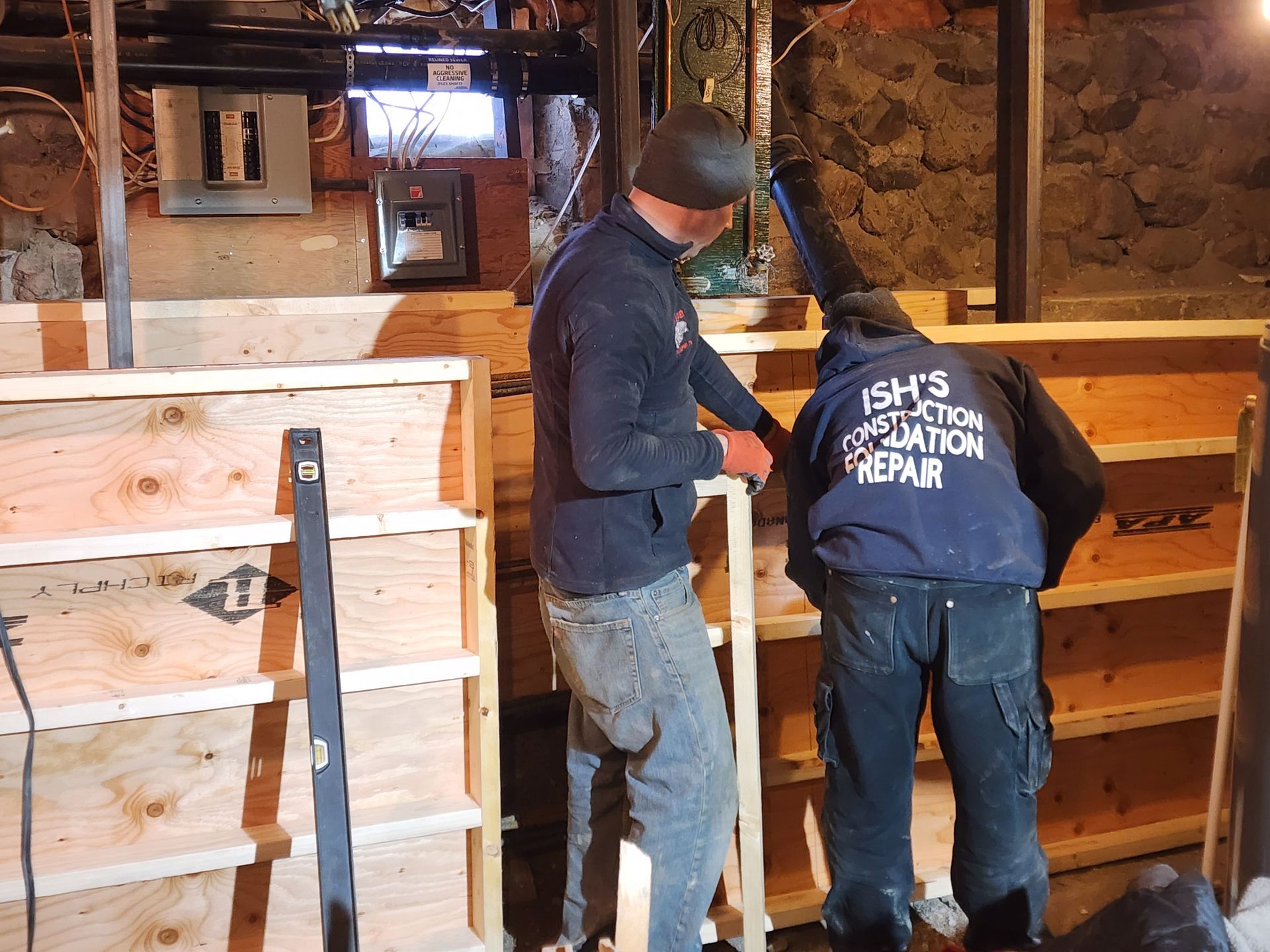 Two workers building wooden form in a basement for pony wall
