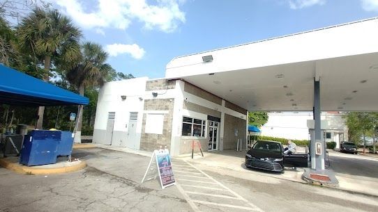 A car is parked in a parking lot in front of a gas station.