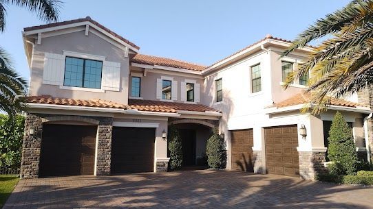 A large house with two garages and a palm tree in front of it