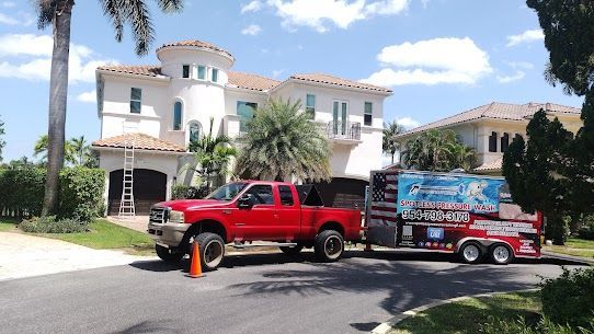 Two red trucks are parked in front of a large white house