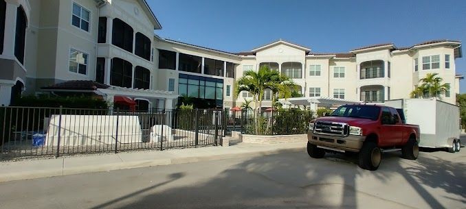A red truck is parked in front of a large building.