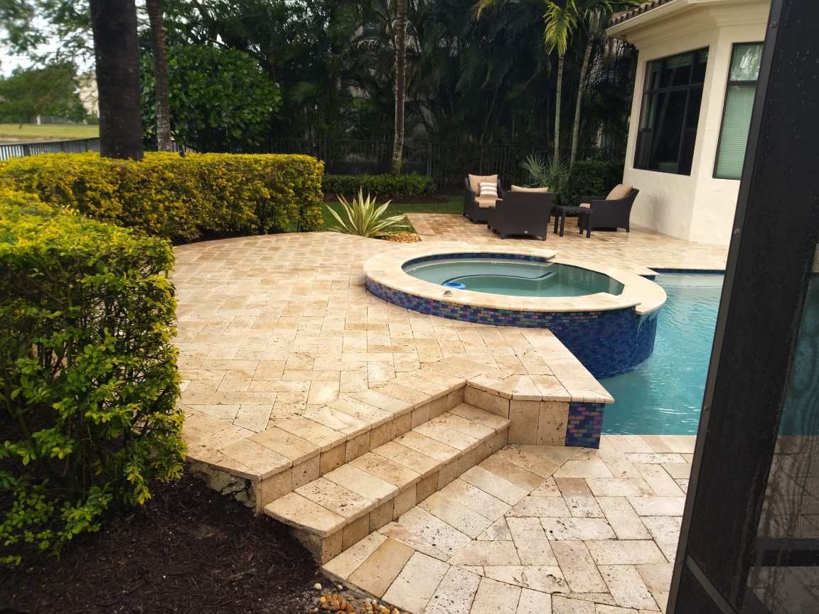 A patio with a hot tub next to a swimming pool.