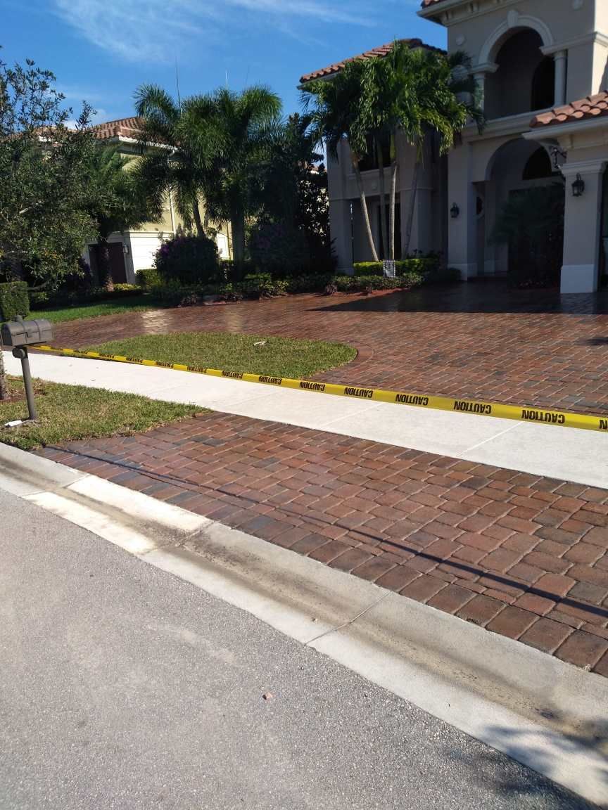 A large house with a brick driveway and a sidewalk in front of it.