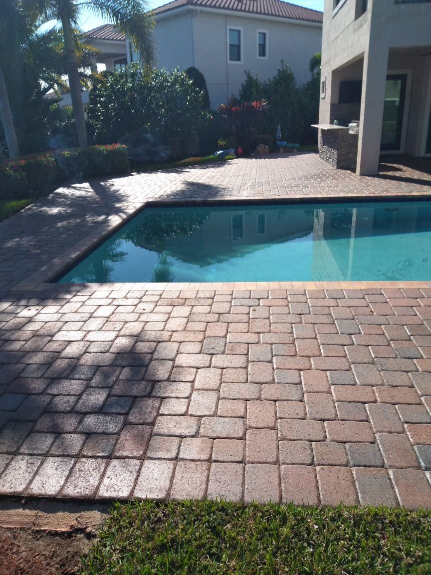 A large swimming pool with a brick patio in front of it