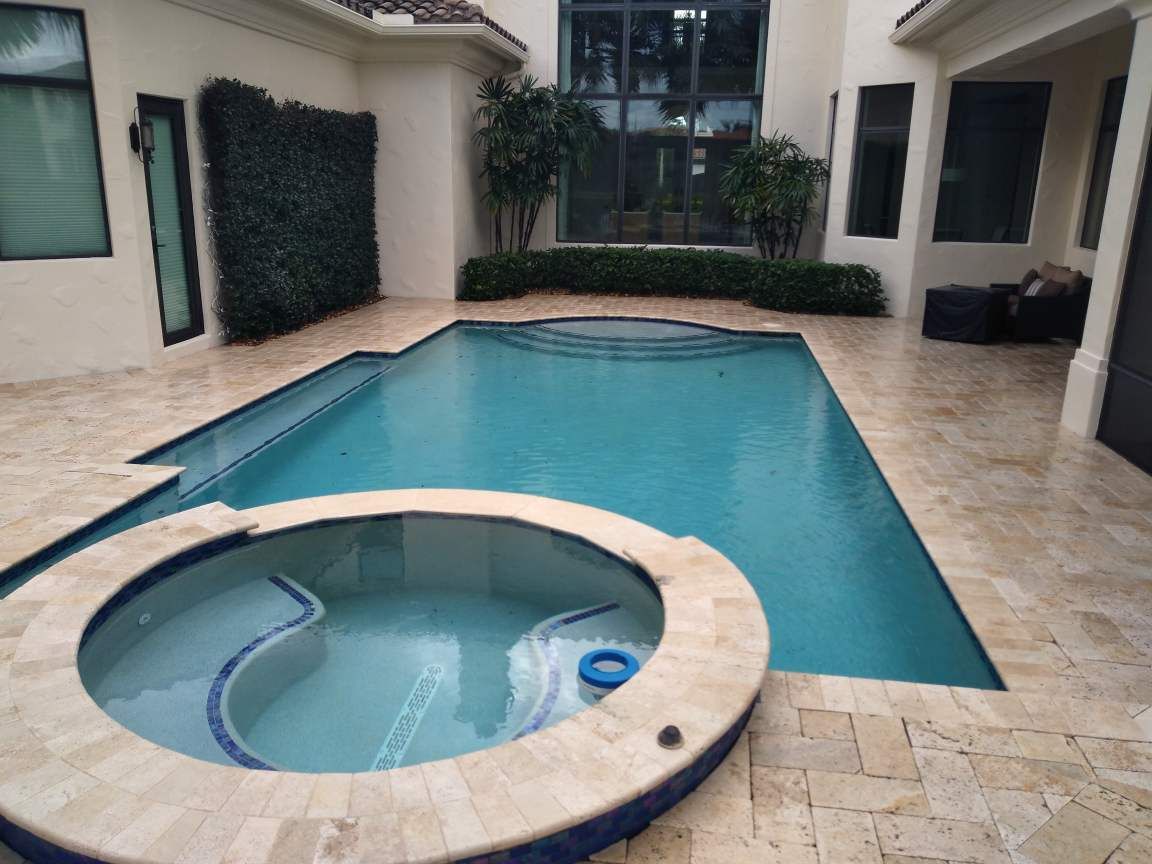 A large swimming pool with a hot tub in the middle of it