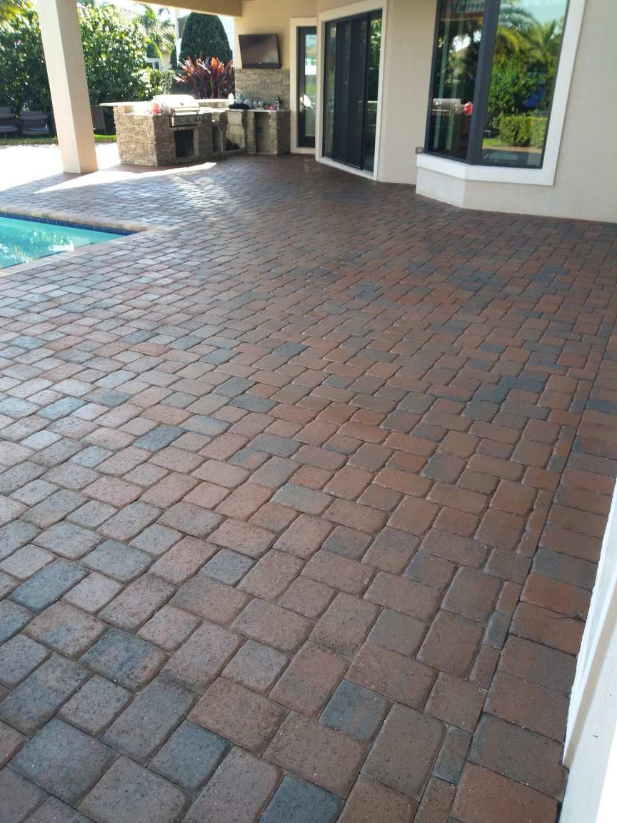 A brick patio with a swimming pool in the background.