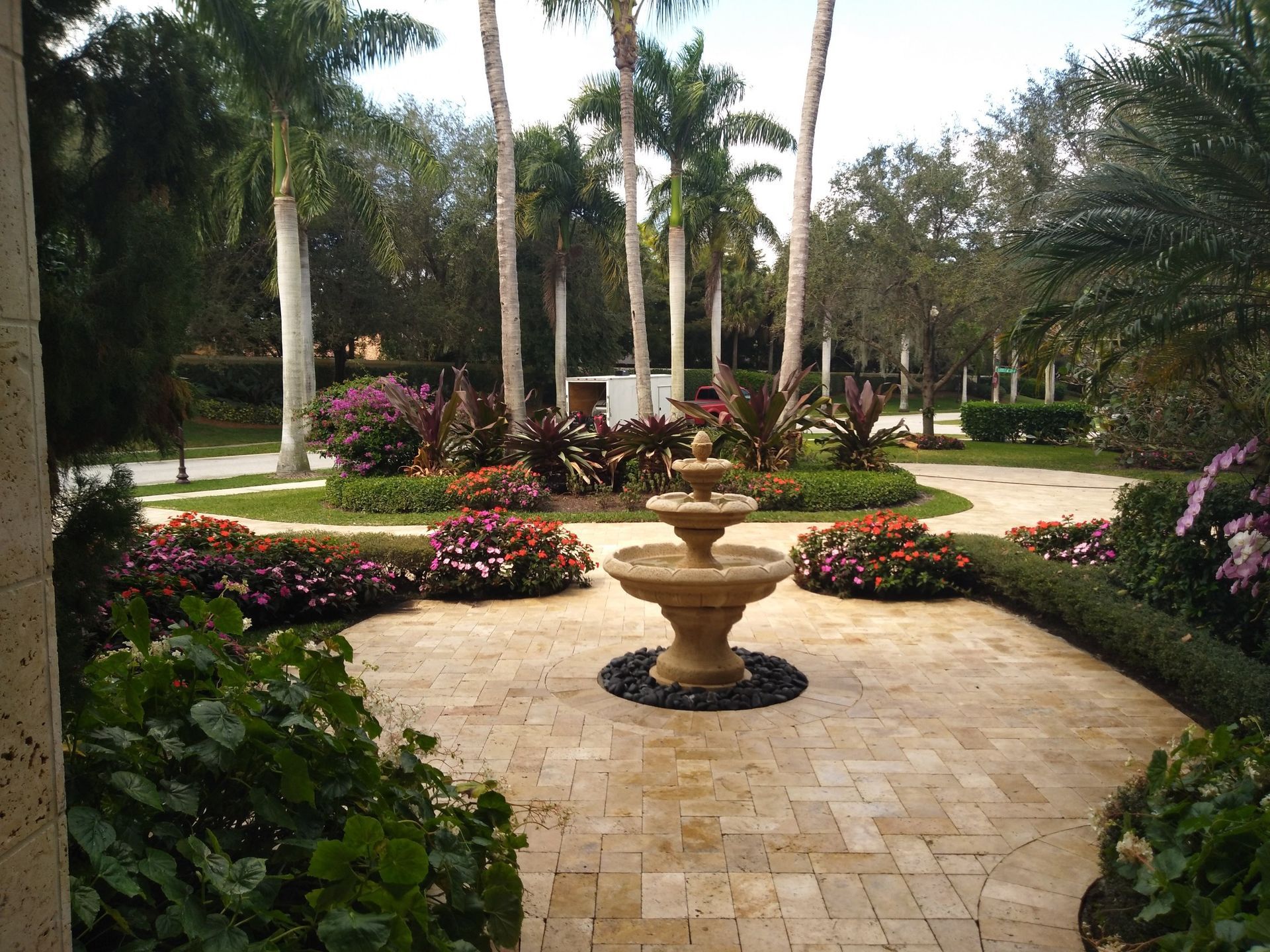 A fountain in the middle of a garden with palm trees