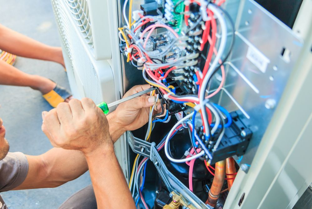 Two People Repairing HVAC System with Screwdriver, Wires Visible — Gilmour Air & Electrical in Cobar, NSW