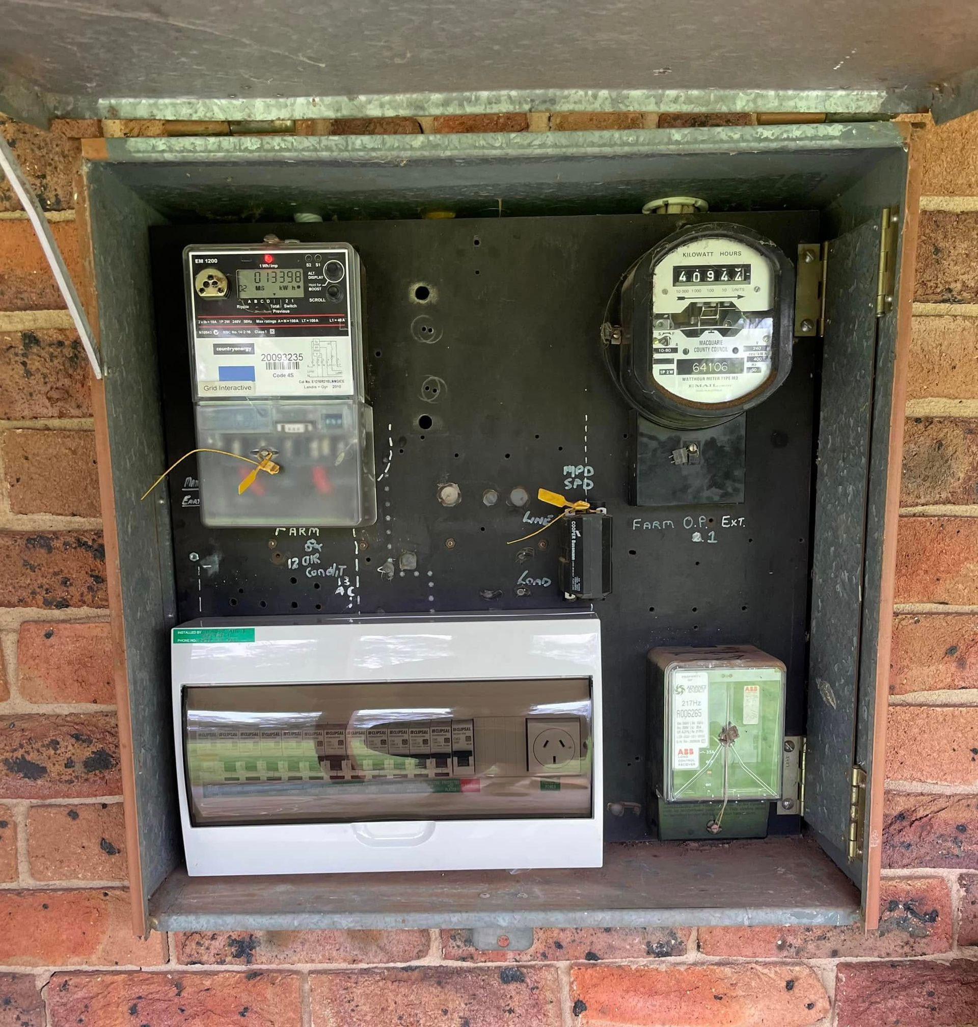 An Electrical Panel on A Brick Wall with Meters, Circuit Breakers, and Wiring — Gilmour Air & Electrical in Dubbo, NSW
