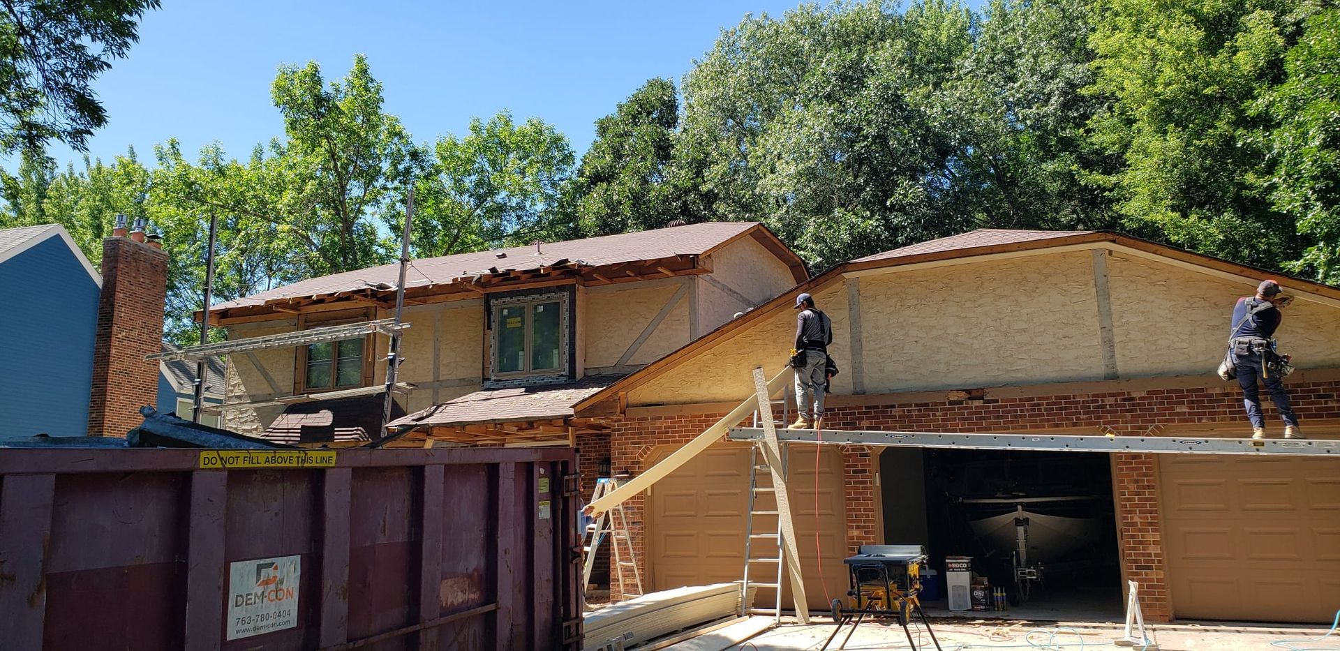 A house is being remodeled with a dumpster in front of it.