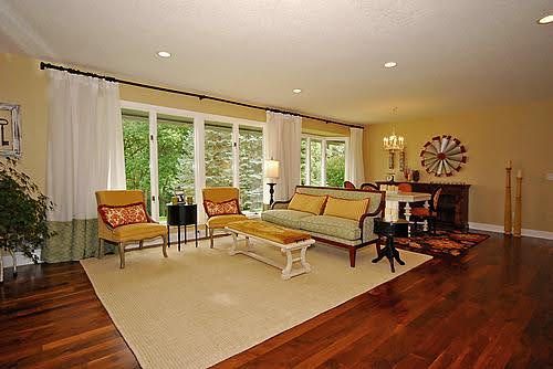 A living room with hardwood floors , a couch , chairs and a table.