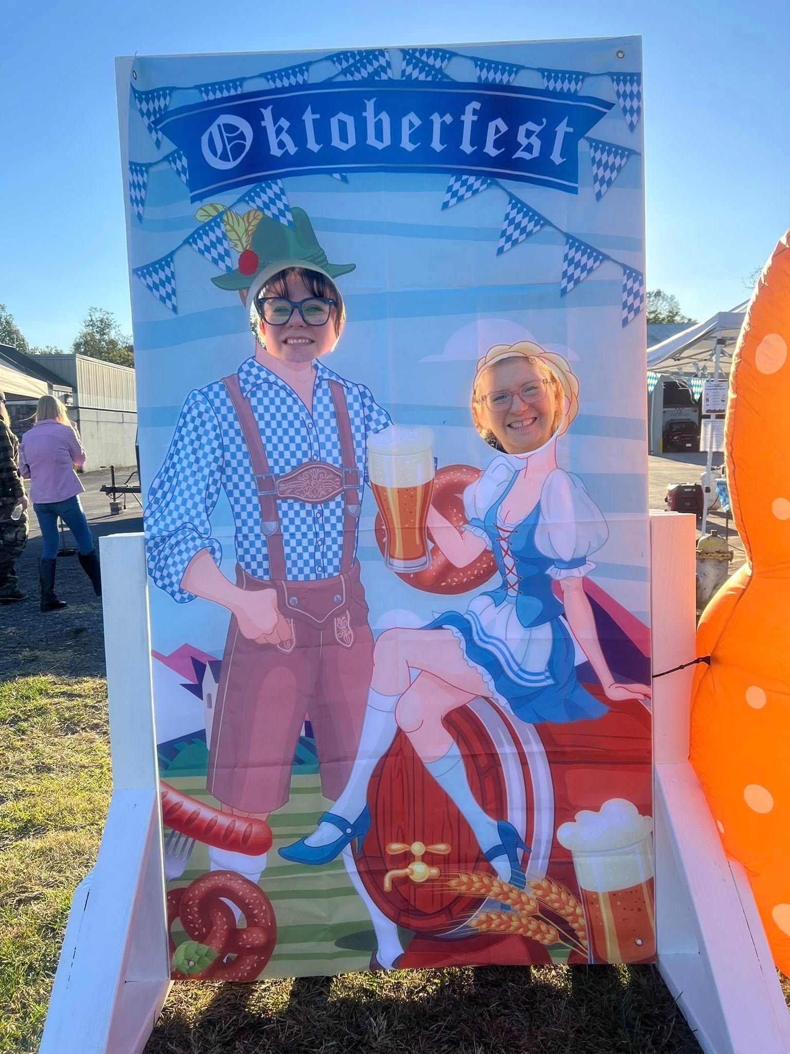 People posing at Oktoberfest cutout, with beer mugs.