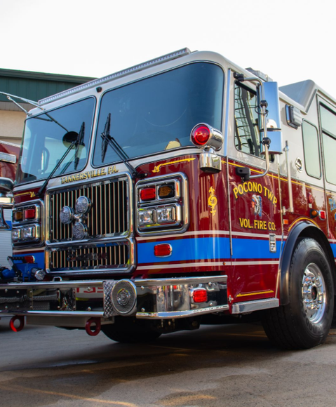 Ambulance with open back doors, emergency lights flashing at dusk.