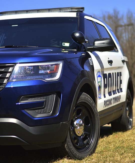 Blue and white Pocono Township police SUV parked on grass.