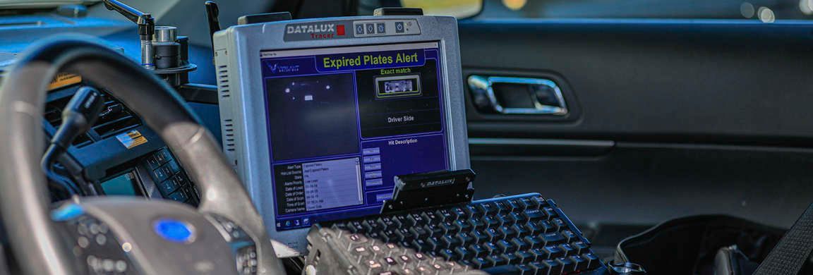 Interior of a police car with a computer and steering wheel.
