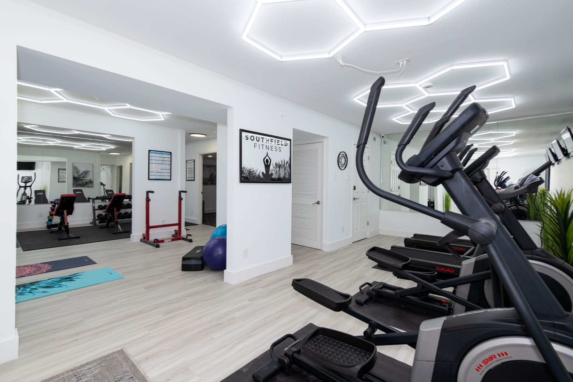 A gym with a lot of exercise equipment and a large mirror.